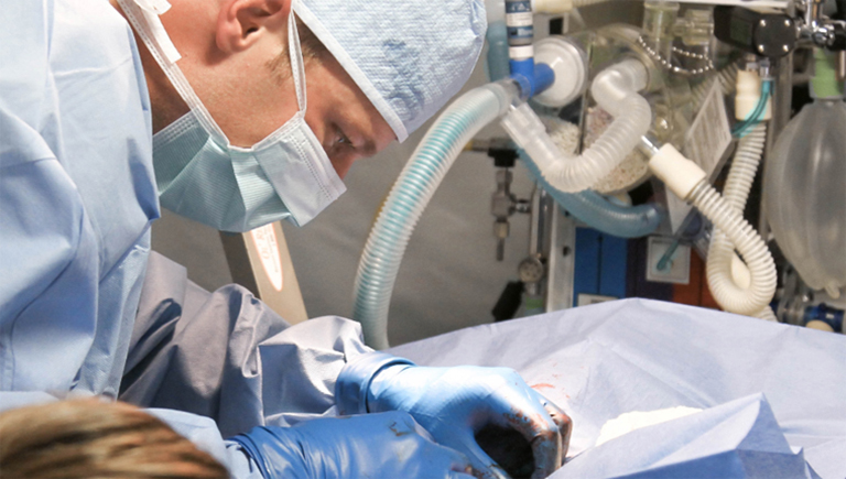 Szene aus einer Operation, Arzt beugt sich über Patienten.